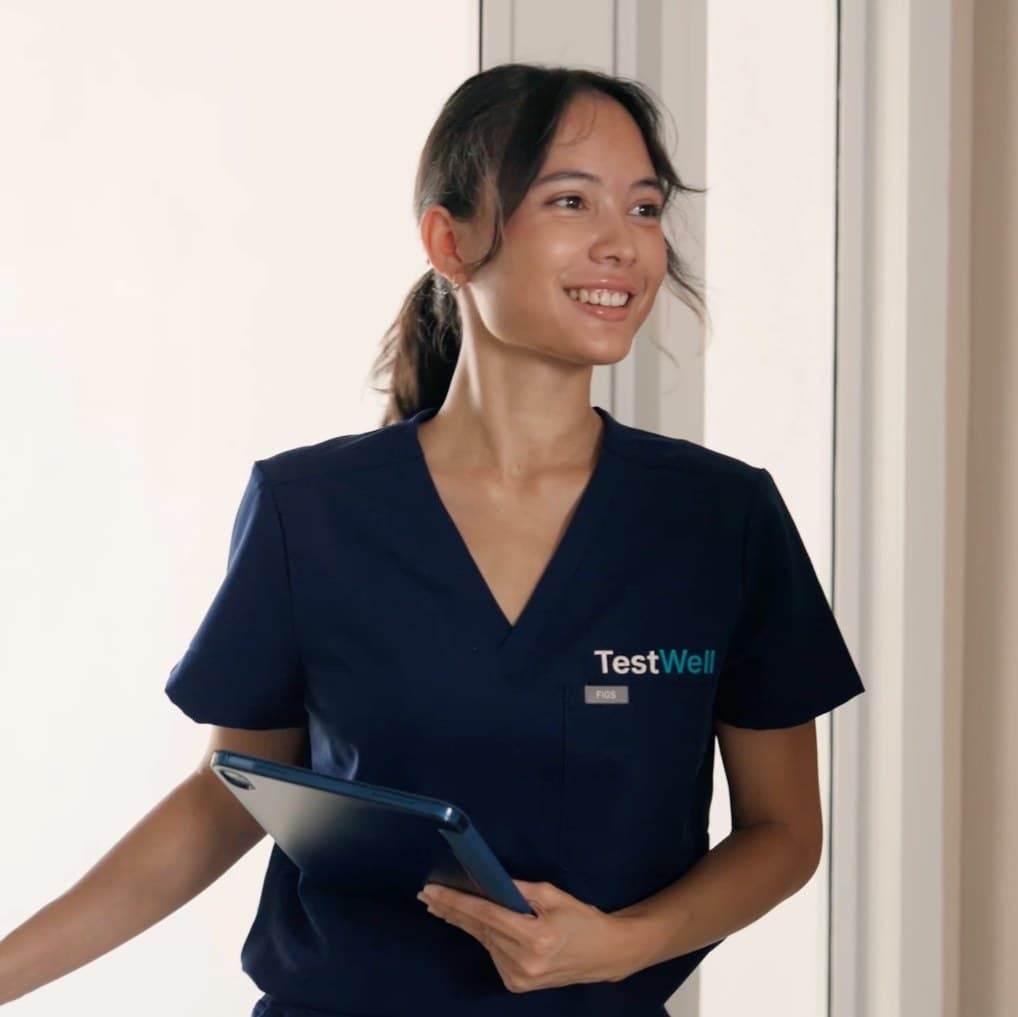 A TestWell nurse in navy scrubs holding a tablet